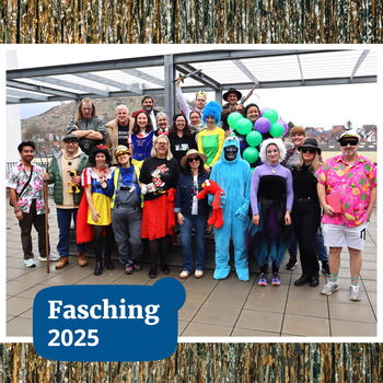 Eine Gruppe von Menschen in bunten Kostümen feiert fröhlich den Fasching 2025 auf einer Terrasse.