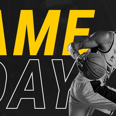 Ein Basketballspieler der MHP RIESEN dribbelt kraftvoll, während "Game Day" in großen gelben Buchstaben erscheint.