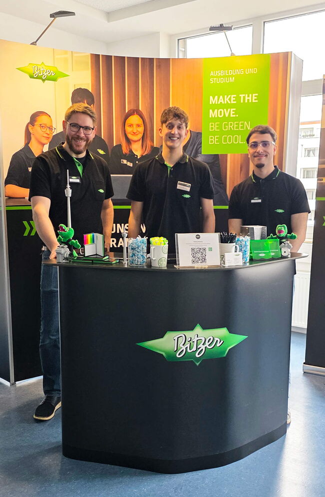 Drei Mitarbeiter von Bitzer stehen lächelnd an ihrem Messestand und präsentieren Informationen zu Ausbildung und Studium.