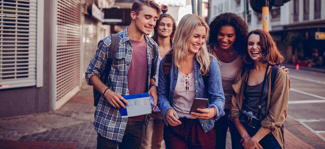 5 Schüler:innen lachen auf einer Strasse