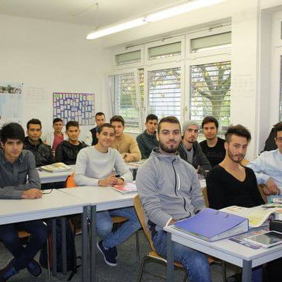 Eine Gruppe von Studierenden sitzt in einem hellen Klassenzimmer und blickt aufmerksam nach vorne.