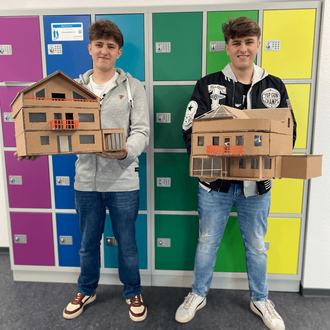 Zwei junge Männer präsentieren ihre Modelle im Schulflur