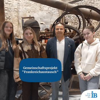 Vier Personen posieren vor einer historischen Maschine für das Gemeinschaftsprojekt "Frankreichaustausch".
