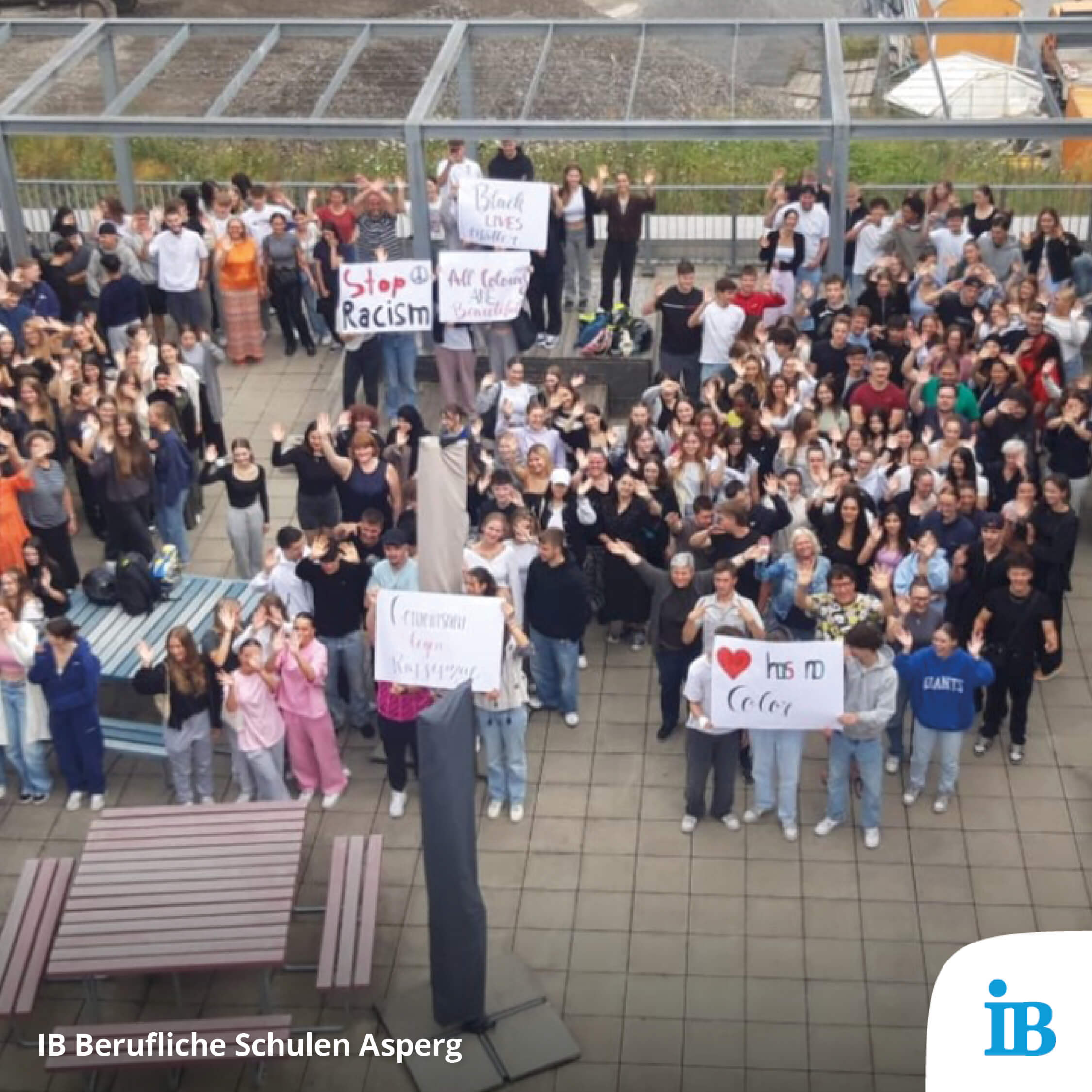 Eine große Gruppe von Schülern in Asperg hält Schilder gegen Rassismus hoch und zeigt Solidarität auf dem Schulhof.