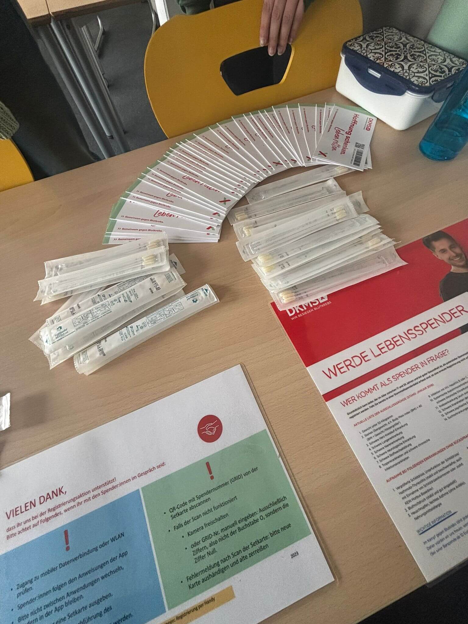 Auf einem Tisch liegen viele Registrierungsunterlagen und Stäbchentests für eine Typisierungsaktion zur Lebensspende aus.