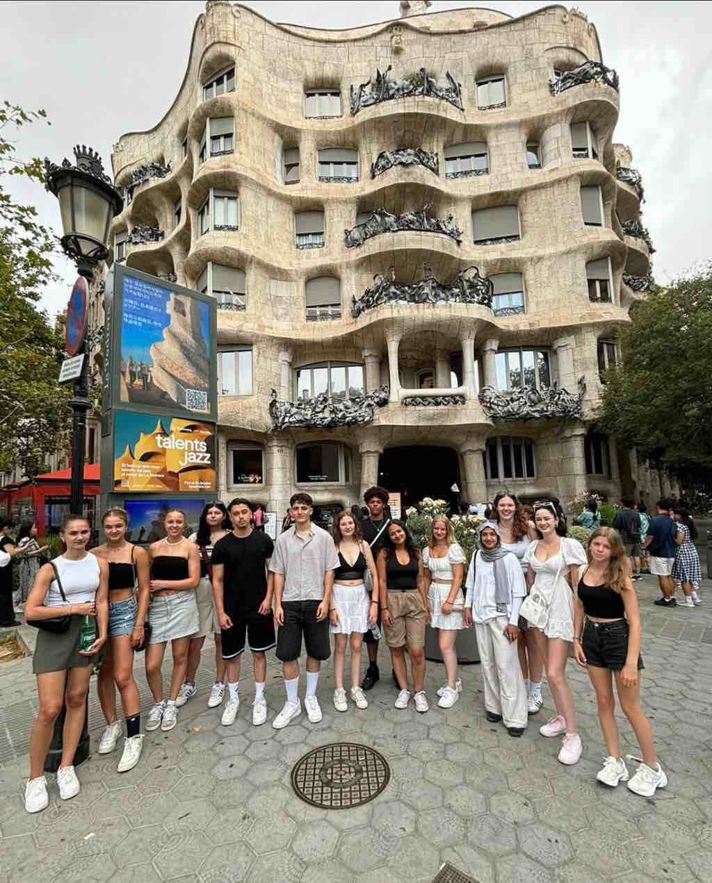 Eine Gruppe junger Menschen posiert vor dem wellenförmigen Gebäude Casa Milà in Barcelona.